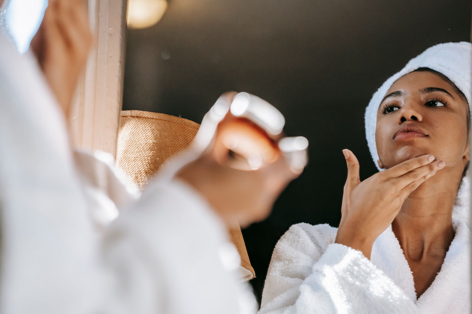 A person applying gentle treatment cream to manage back acne in a well-lit room.